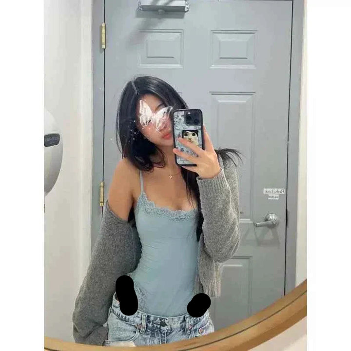 امرأة ترتدي بودي سوت دانتيل كلاسيك SKIMS بلون أزرق فاتح مع كاردغان رمادي وتلتقط صورة السيلفي أمام مرآة
