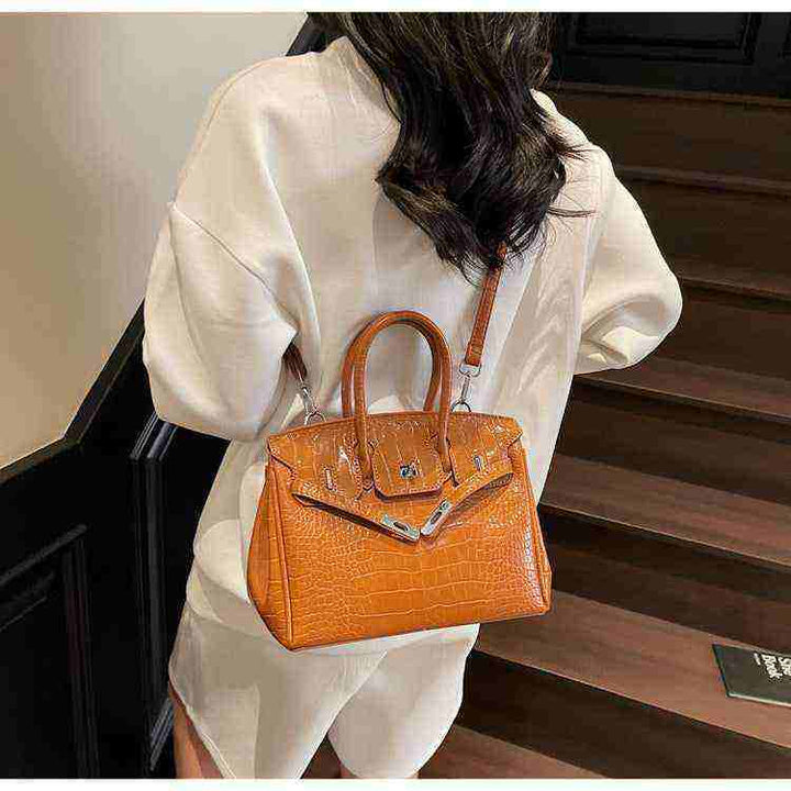 Women's Birkin-style handbag with crocodile pattern in orange leather, high-quality Chinese craftsmanship, crossbody and top-handle design.