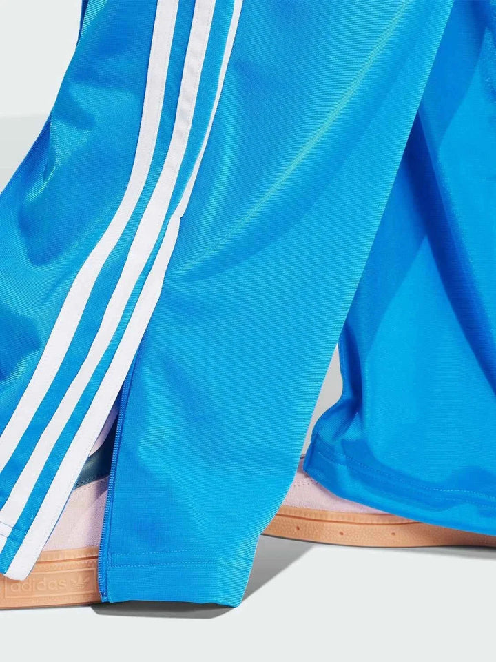 blue Adidas sports pants with white stripes and zipper pockets