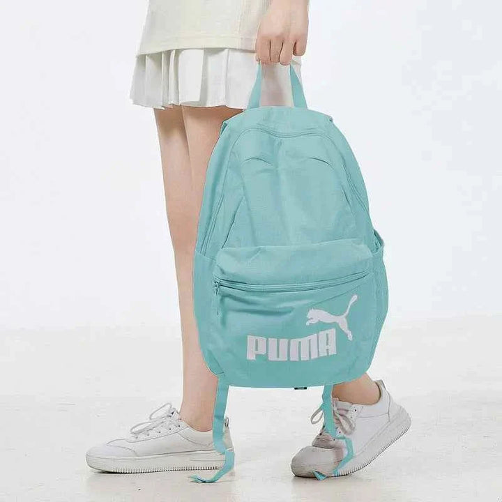 Light blue PUMA backpack with main and front zip pockets, durable material, adjustable padded straps, suitable for school and daily use.