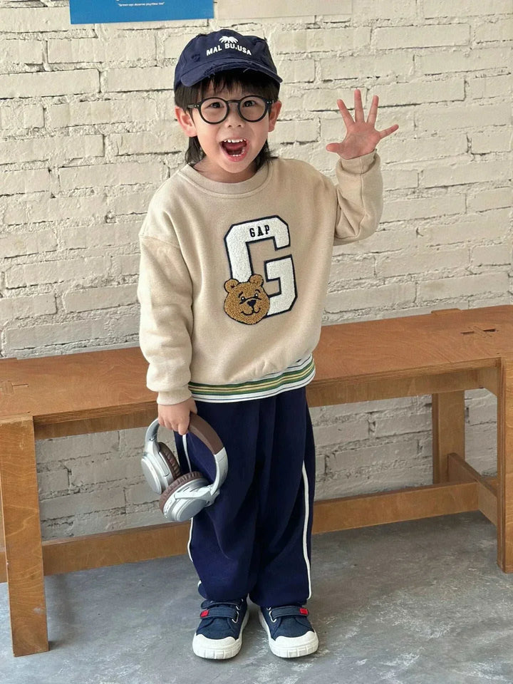 طفل يرتدي سويت شيرت غاب بير بتصميم أنيق ودافئ مع شعار دب ونقشة حرف G كبير على الصدر