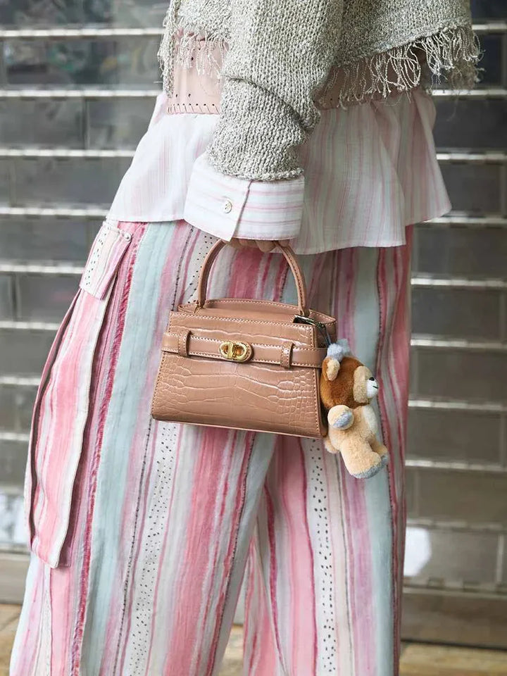 Cute bear keychain with reindeer antlers hanging on a brown handbag