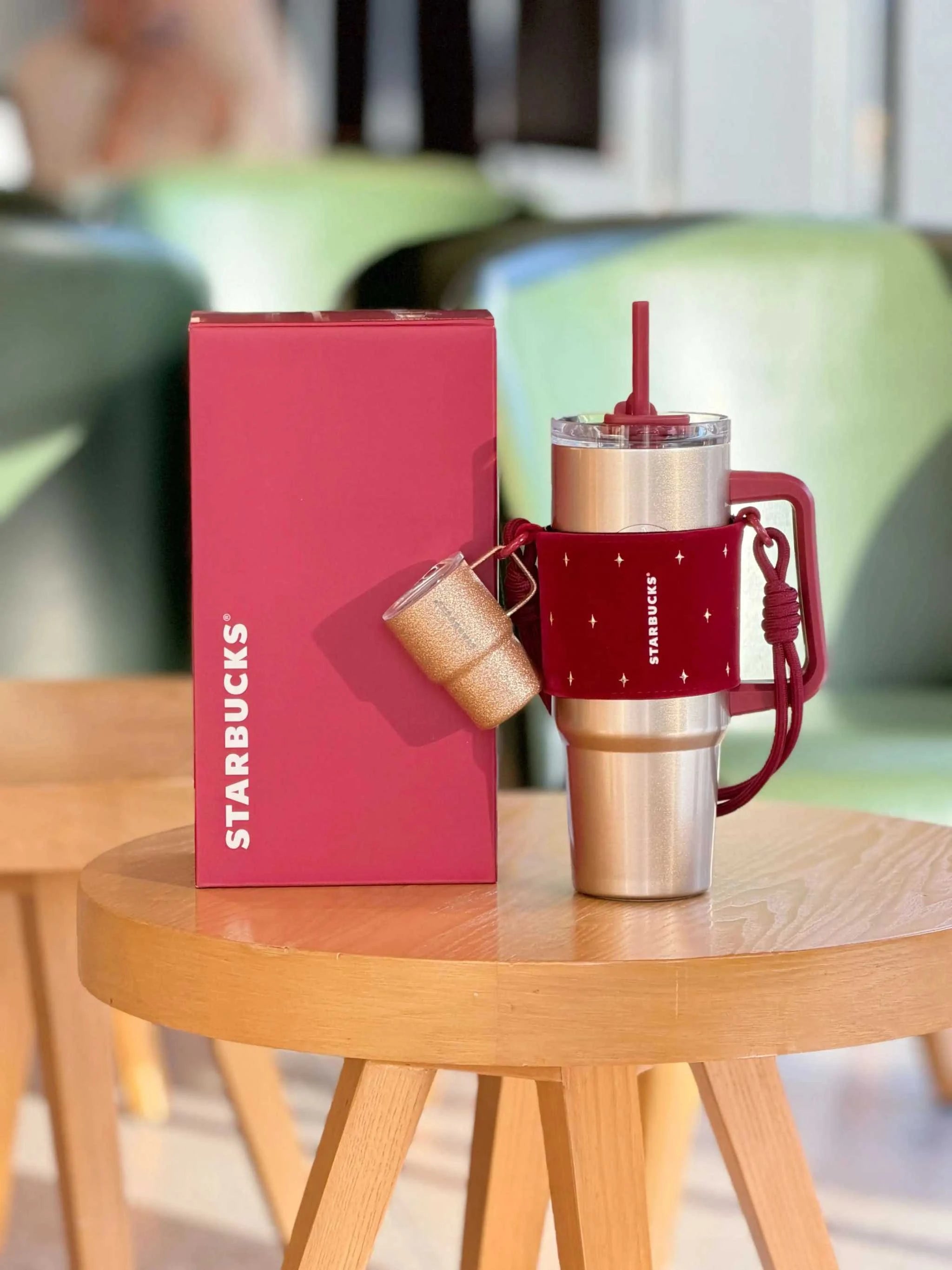 كوب Tumbler من Starbucks ذهبي مع حامل أحمر فاخر.
