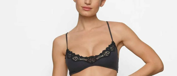 woman wearing black SKIMS FITS EVERYBODY lace scoop bralette and matching lace camisole vest lingerie set