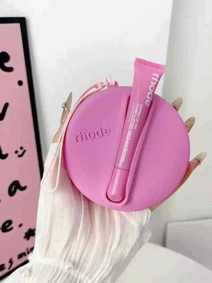 Rhode Peptide Lip Tint in pink with matching round silicone pouch held in hand