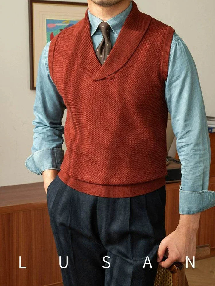 Mr. Lusan warm sweater vest in rust red with shawl collar, knit texture, and ribbed edges worn over a blue shirt and black trousers