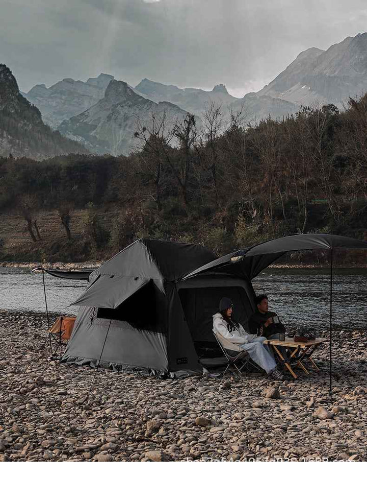 Wolf Walker Cloud Pavilion inflatable camping tent with large canopy set up on rocky riverbank in mountainous outdoor setting