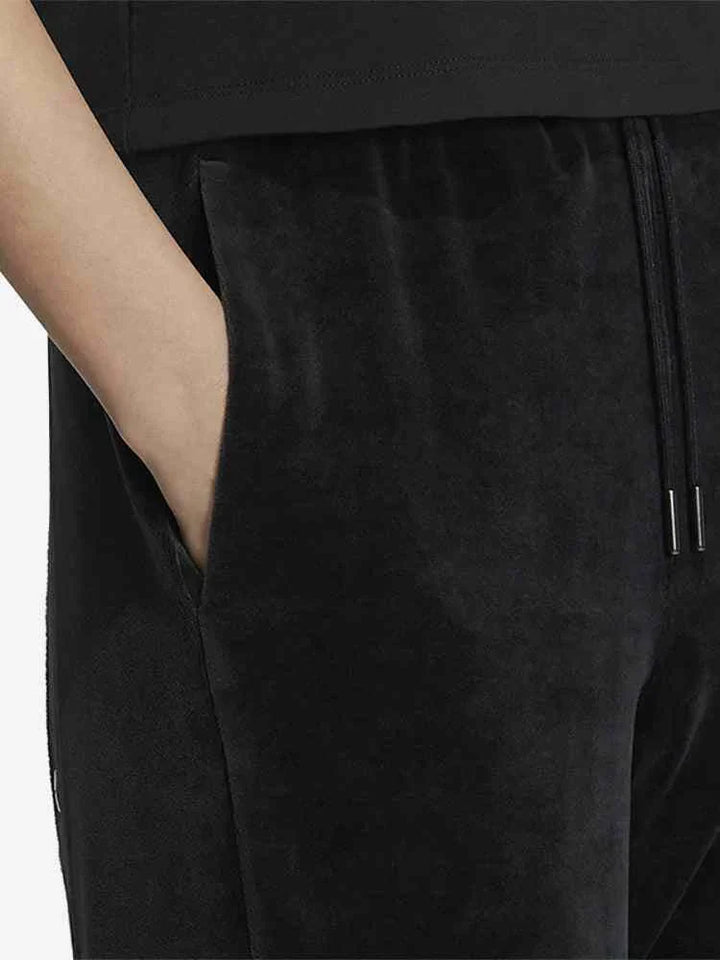 Black Adidas sports pants with white side stripes and adjustable waistband close-up showing pocket detail