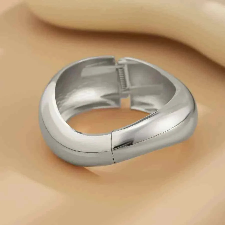أساور Chunky عريضة بتصميم انسيابي عصري باللون الذهبي والفضي.
