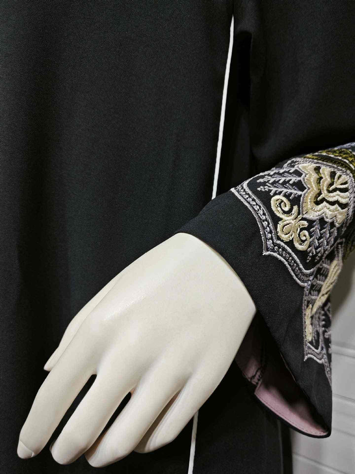 Elegant black abaya with intricate gold embroidery on sleeves, suitable for formal or casual occasions.