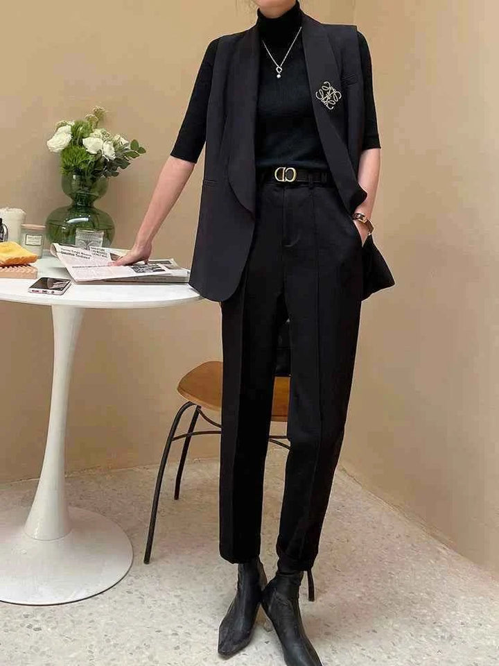 Black formal pants with a classic comfortable cut made from luxurious fabric, styled with a black sleeveless blazer and ankle boots.
