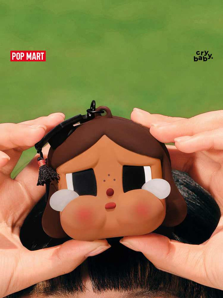 حافظة سماعة بتصميم كراي بيبي الحزين مع قبعة تخرج من Pop Mart.