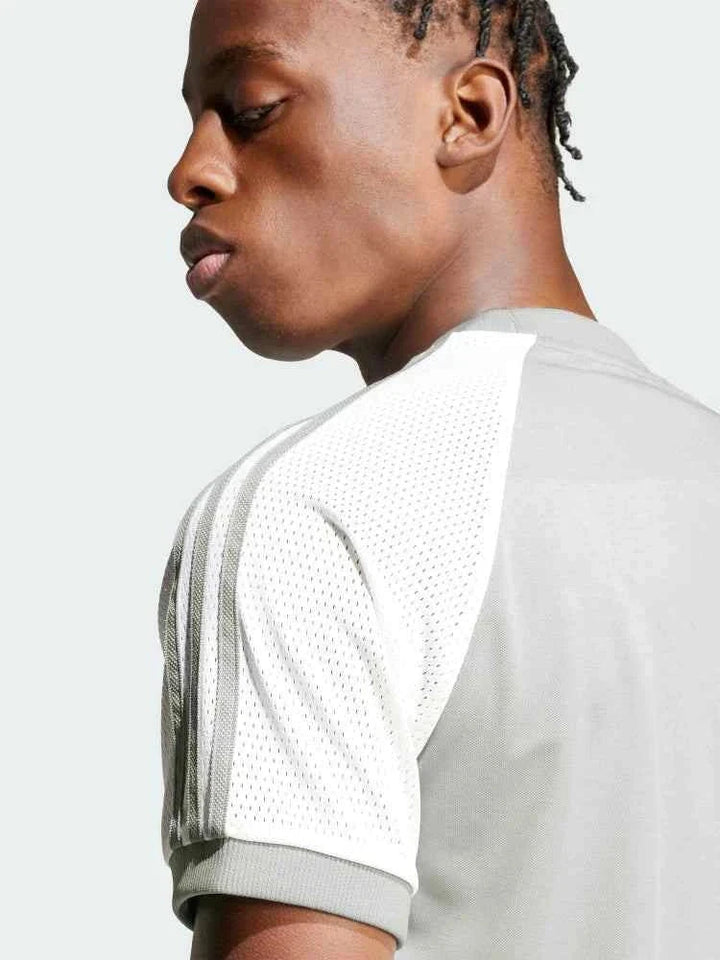 رجل يرتدي Adidas تيشيرت رياضي عصري بأكمام راجلان بلون رمادي فاتح مع جوانب بيضاء شبكية وشعار أديداس الثلاثي