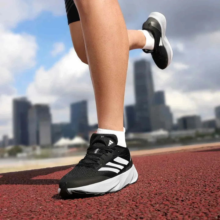 Adidas أديداس حذاء الجري السريع ADIZERO SL أسود أبيض للرجال والنساء على مضمار الجري بخلفية مدينة
