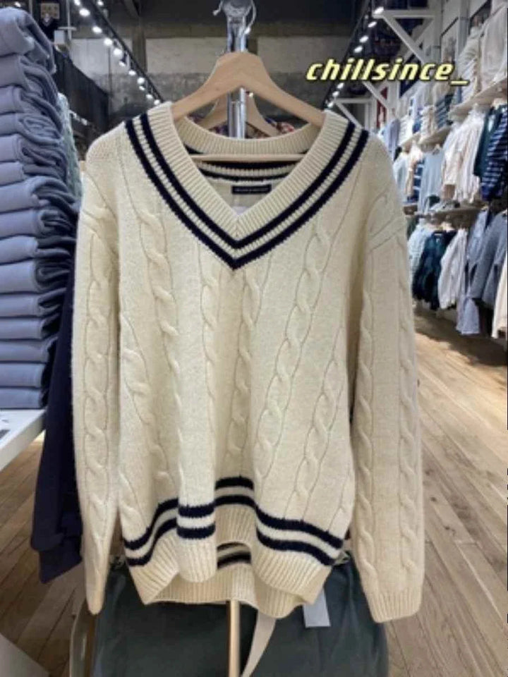 Classic winter sweater with cable knit design and striped edges in off-white color