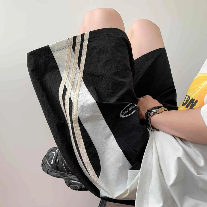 Black sporty shorts with side stripes in beige and white, lightweight and comfortable design for casual and active wear