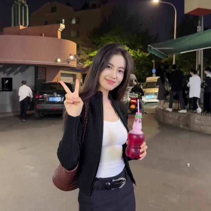 Woman wearing SKIMS square neck tank top holding a drink outdoors at night