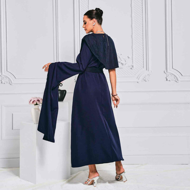 Elegant navy cape dress with embroidery and flowing sleeves, perfect for upscale occasions.