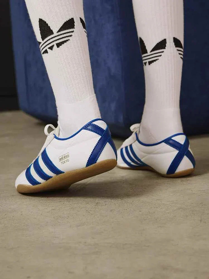 Adidas حذاء نسائي كلاسيكي خفيف بنعل رفيع أبيض وأزرق مع خطوط جانبية وتصميم عصري للرياضة والمشي