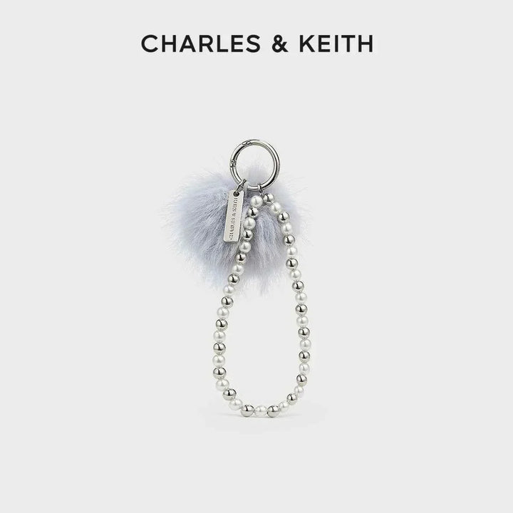 ميدالية تشارمز أنيقة من CHARLES & KEITH مع خرز فضي وقطعة فرو ناعمة بتصميم مميز يعكس الأناقة والستايل الشخصي