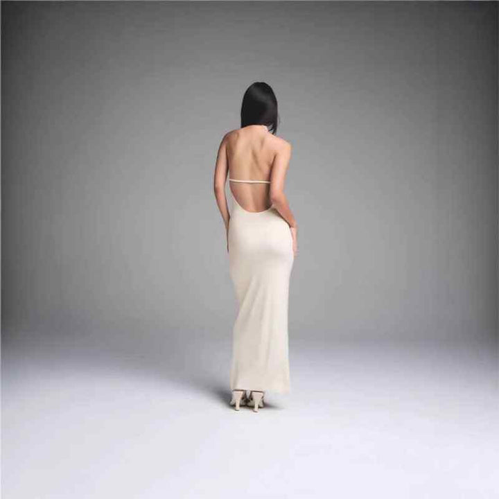 Woman wearing SKIMS فستان طويل open back maxi dress with thin straps and fitted silhouette in beige color