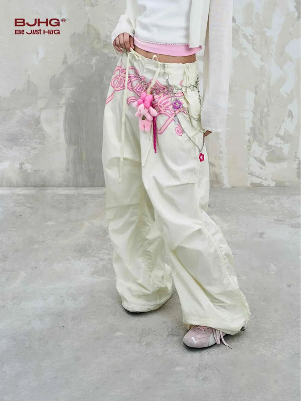 white wide embroidered pants with pink decorative stitching and tassels, casual loose fit streetwear style