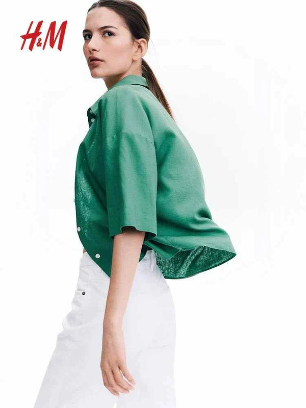 Green shirt from H&M, worn by a model with white pants against a white baاتش اند امckground.