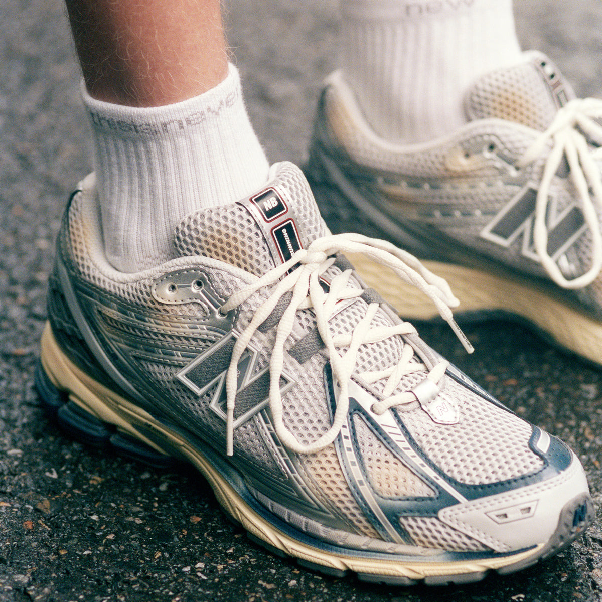 On-foot lifestyle close-up view of metallic silver and navy blue New Balance shoes 1906R.