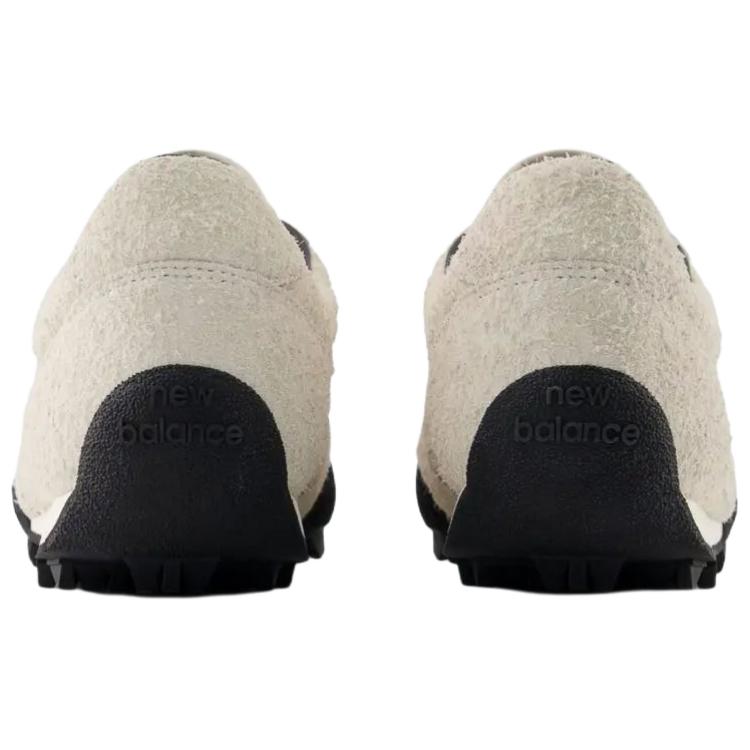 Rear heel view of a pair of Donald Glover x New Balance RC30 "Sea Salt" shoes, featuring textured hairy beige suede heels, dark collar linings, and an extended black rubber outsole wrap stamped with "new balance" text branding.
