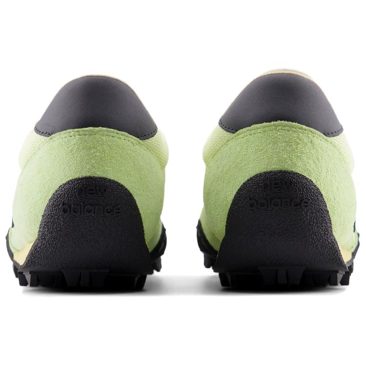 Rear heel view of a pair of light green and black New Balance RC30 shoes, featuring bright lime green suede heel counters, dark grey leather heel tabs, and an extended black rubber outsole wrap stamped with "new balance" text branding.