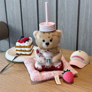 Clear Starbucks strawberry bear cup standing on a pink textured mat, displaying the complete product for كوب ستاربكس الدبدوب الوردي 2026 آخر اصدار.