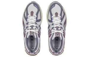 Top-down aerial view of a pair of grey and purple New Balance shoes 1906R model, displaying off-white mesh uppers, slate grey and metallic mauve overlays, cream laces, grey padded collar lining, and grey branded OrthoLite insoles.