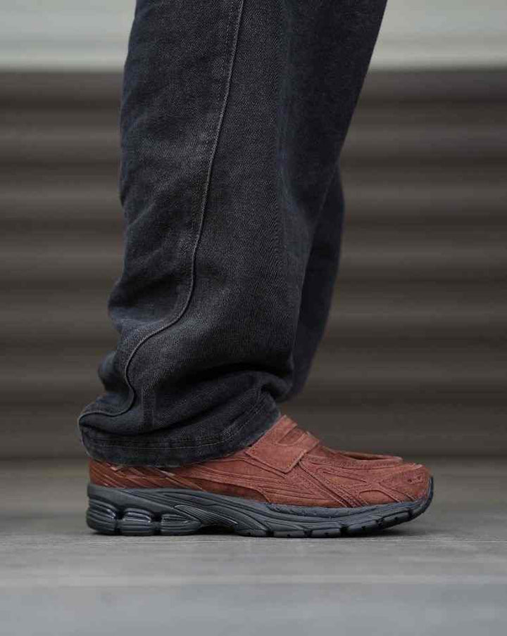 Brown New Balance 1906 sneaker with mesh and metallic leather layers, worn with dark pants.