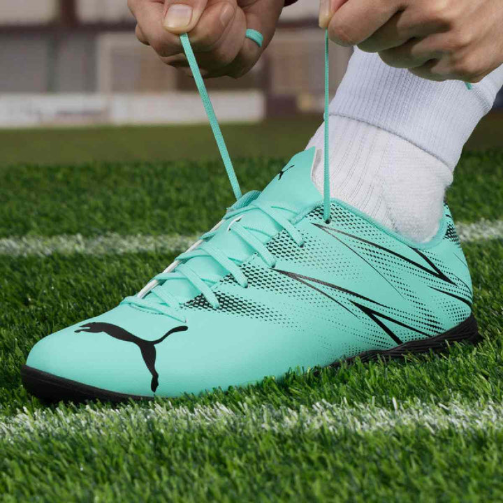 Puma turquoise and black football shoe, designed for artificial grass surfaces.