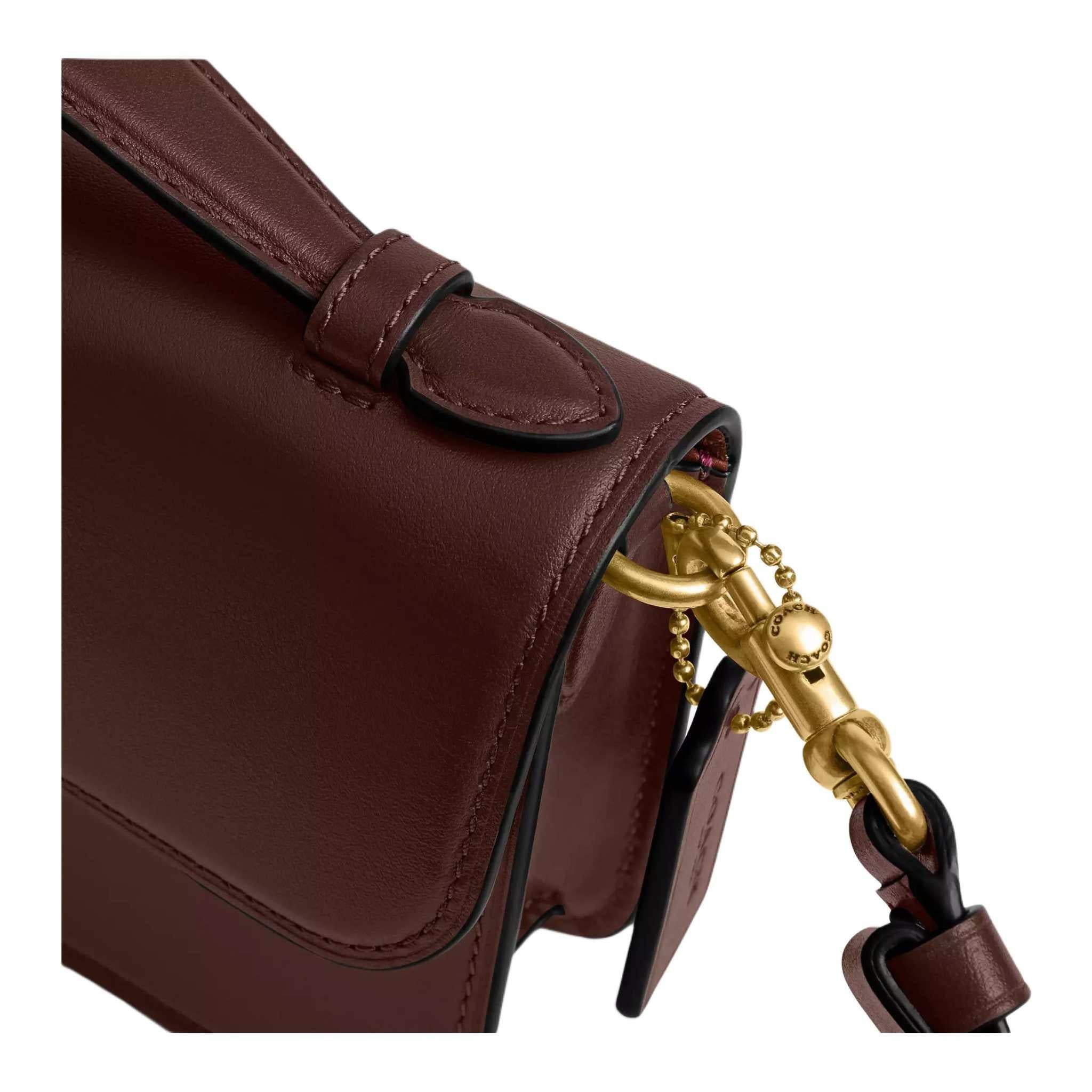 حقيبة كتف Coach بتصميم كلاسيكي أنيق باللون العنابي.