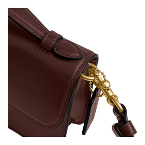 حقيبة كتف Coach بتصميم كلاسيكي أنيق باللون العنابي.