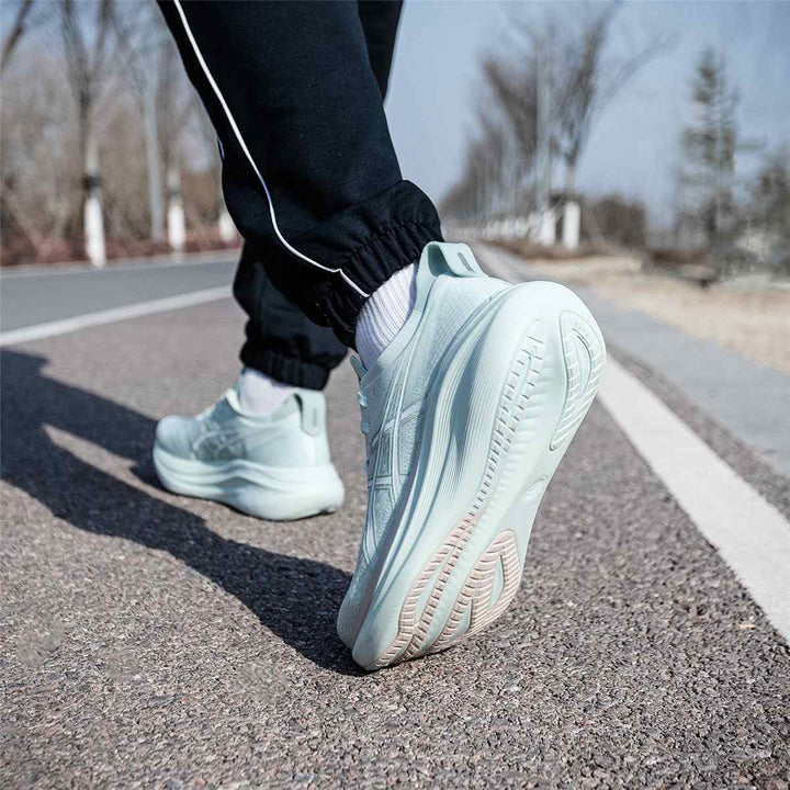 ASICS Gel-Nimbus 27 running shoes, light green, on asphalt road.