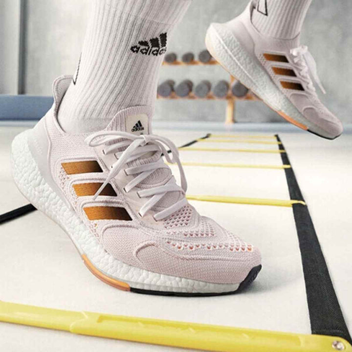 adidas حذاء رياضي بخامات شبكية، وسادة Boost، ولمسات برتقالية مميزة.