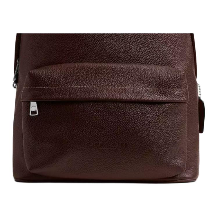 Close-up view of the front zipped pocket and embossed logo on an authentic Coach Westway 32 dark burgundy leather backpack.

عرض قريب للجيب الأمامي ذي السحاب والشعار البارز على حقيبة ظهر كوتش ويست واي 32 أصلية جلد باللون العنابي الداكن.
