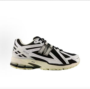 New Balance shoes 1906R sneaker in black and metallic silver, medial profile view displaying white synthetic leather overlays, N-lock support lace webbing, and N-ergy shock-absorbing soles.