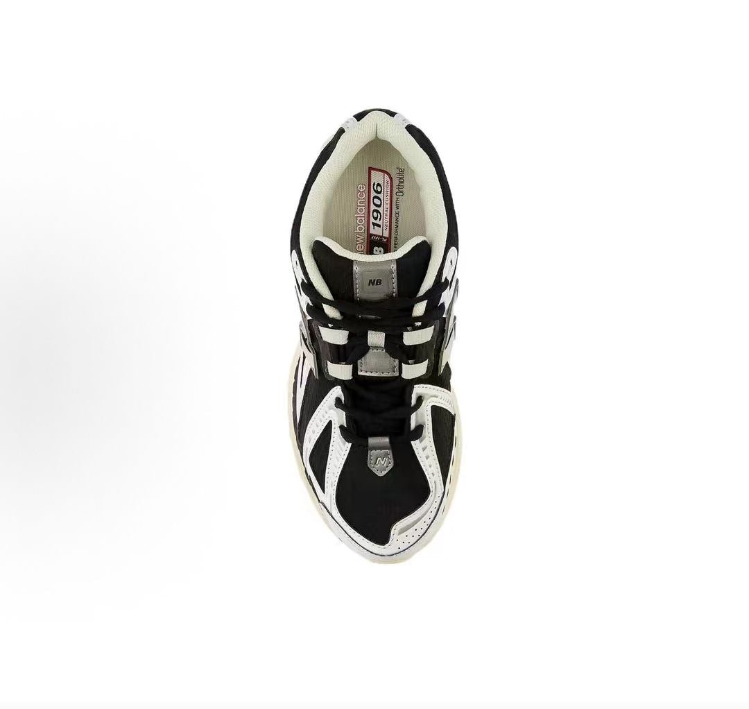 New Balance shoes 1906R running sneaker in black and white, top-down perspective showing black mesh uppers, white leather structural toe overlays, tongue lace-loop branding, and Ortholite inner soles.