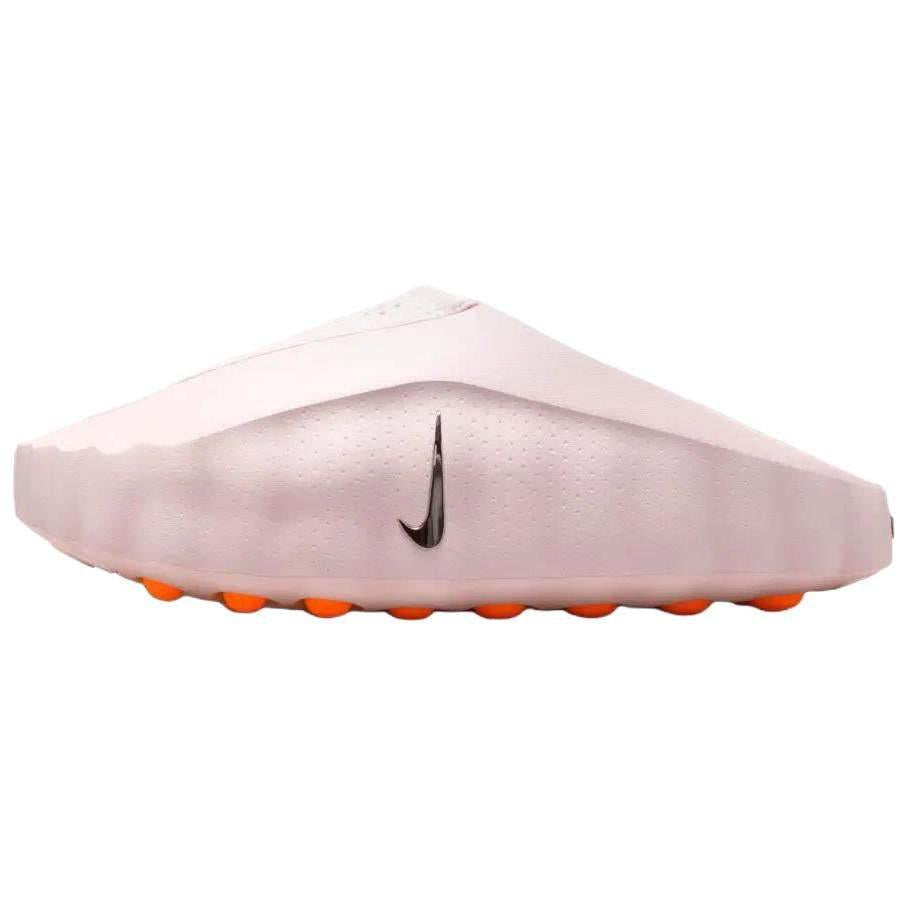 Side profile view of the Nike Mind 001 slip-on shoe in soft baby pink, showcasing its clean structural design, a black swoosh, and bright orange outsole pods.