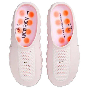 Top-down view of the Nike Mind 001 shoes in baby pink, showing the branded footbeds and bright orange circular cushion pods inside.
