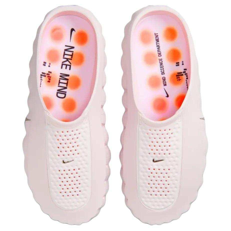 Top-down view of the Nike Mind 001 shoes in baby pink, showing the branded footbeds and bright orange circular cushion pods inside.