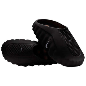 Angular view of a pair of Nike Mind 001 black shoes, displaying the textured upper mesh structure and ergonomic slip-on shape.