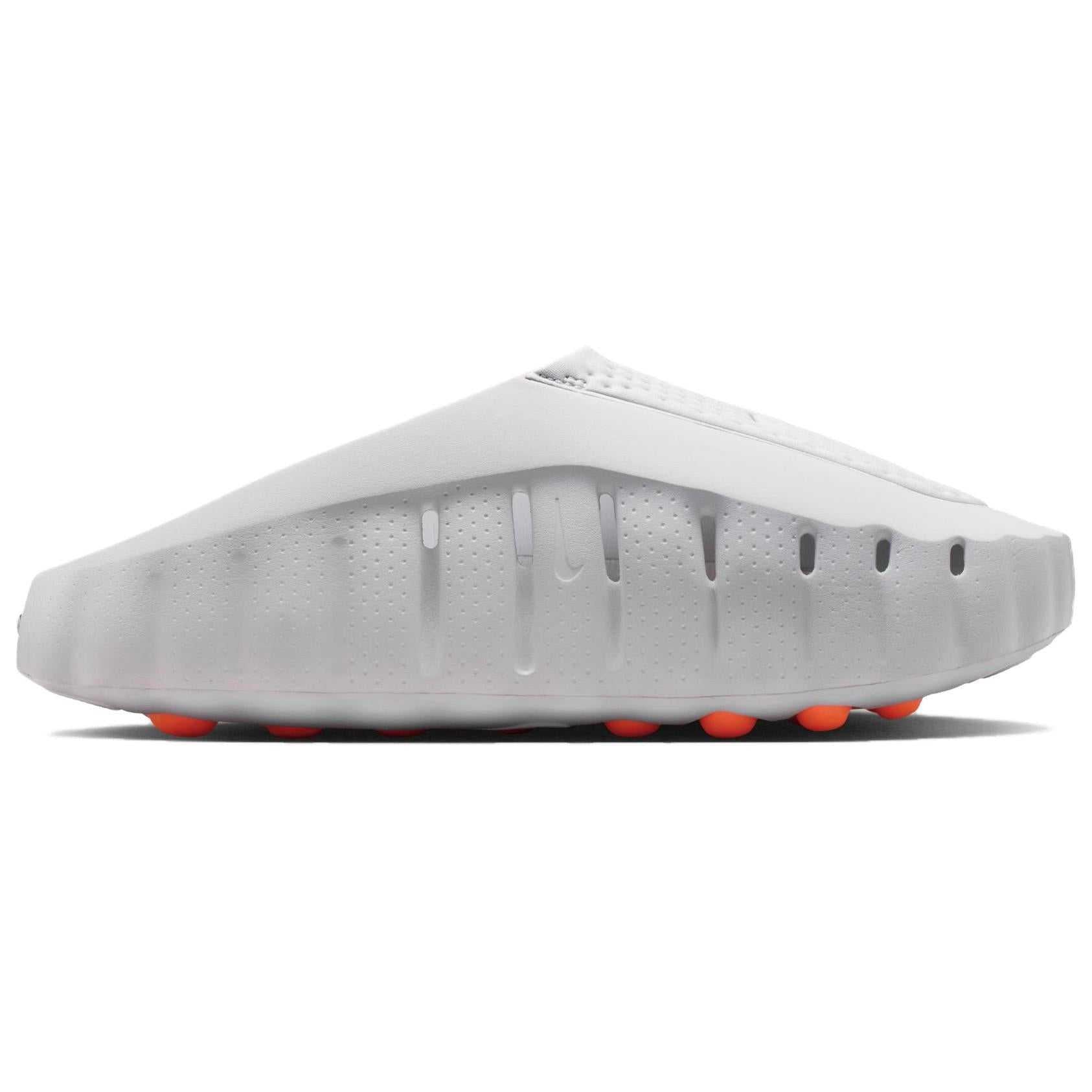 Studio profile shot of the Nike Mind 001 foam shoes, highlighting the minimalist one-piece modular design and the bright orange pods on the outer sole.