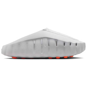 Studio profile shot of the Nike Mind 001 foam shoes, highlighting the minimalist one-piece modular design and the bright orange pods on the outer sole.