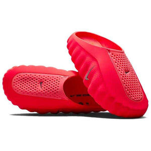 Angular view of a pair of Nike Mind 001 neon red shoes, displaying the mesh texture on the upper and the slip-on design.