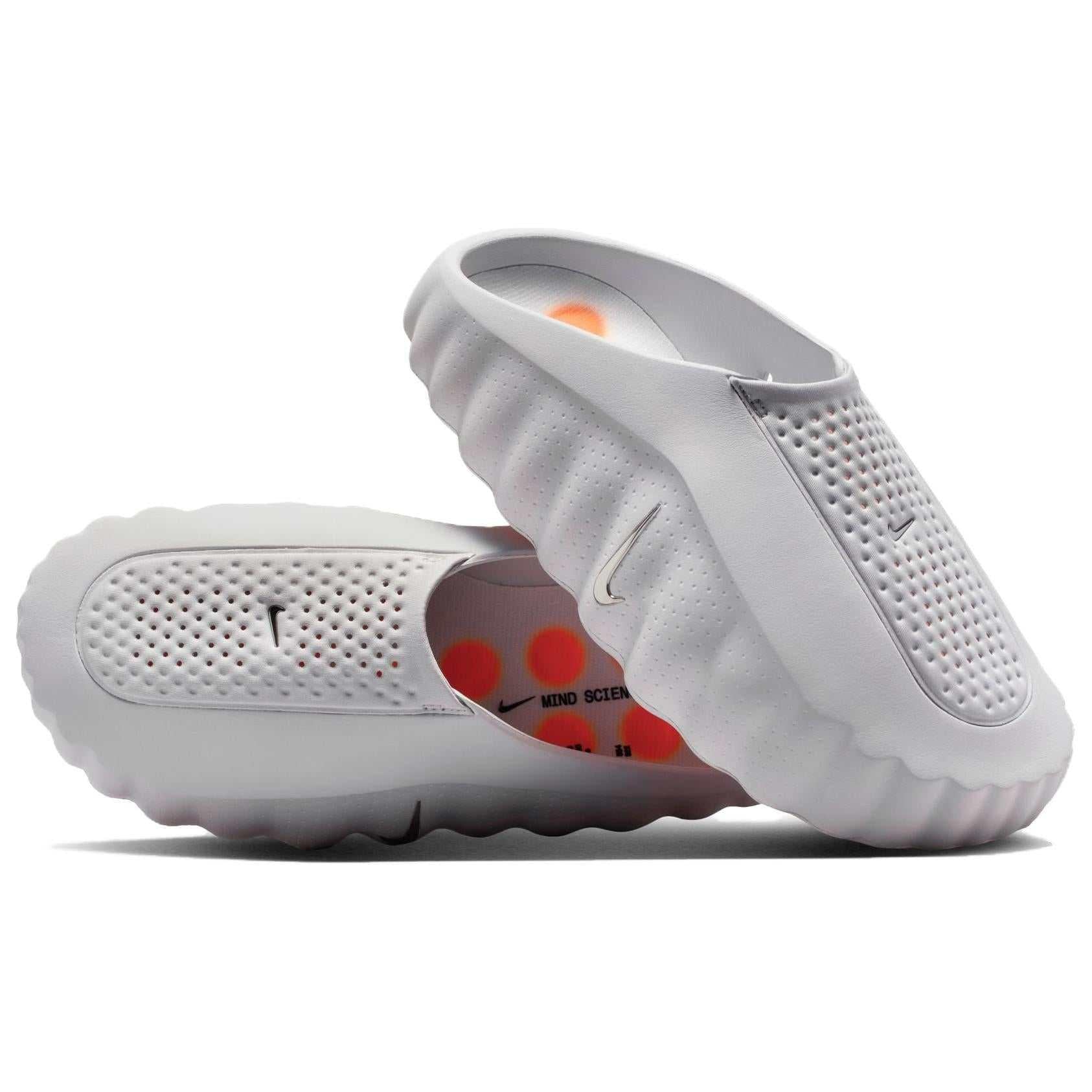 A pair of grey Nike Mind 001 sustainable slides displayed at a dynamic angle, showing the breathable textured upper construction and sensory insoles.