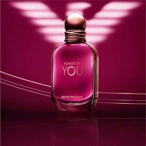 The power of you armani original perfume bottle standing on a reflective surface with a glowing Armani eagle logo background.